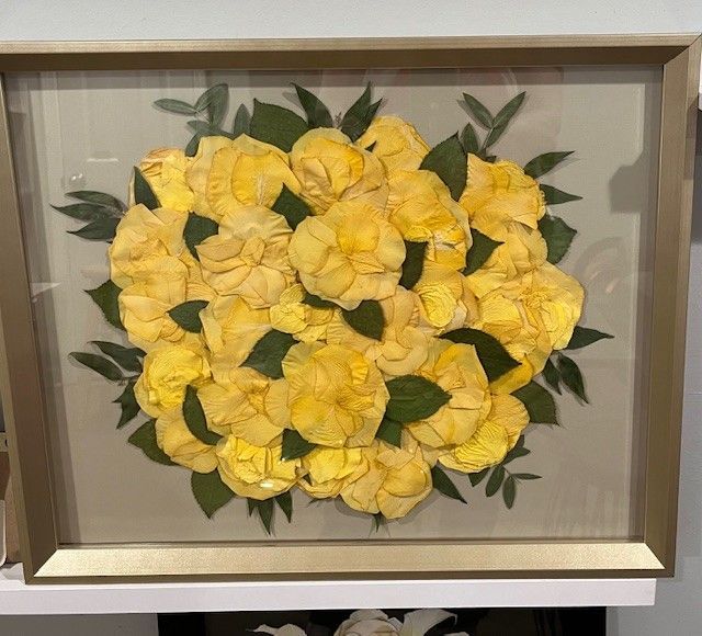 A picture of yellow flowers and green leaves in a frame