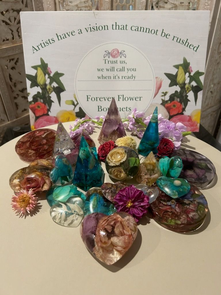 A table topped with flowers and crystals with a sign that says `` artists have a vision that cannot be rushed ''.