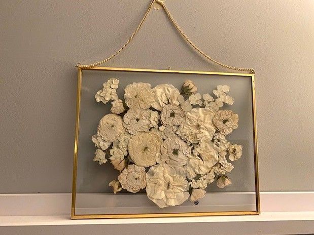 A picture of flowers in a glass frame hanging on a wall.