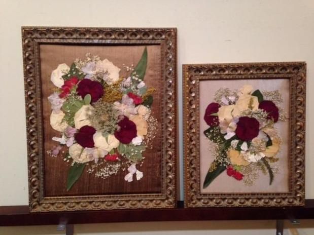 Two framed pictures of flowers on a shelf