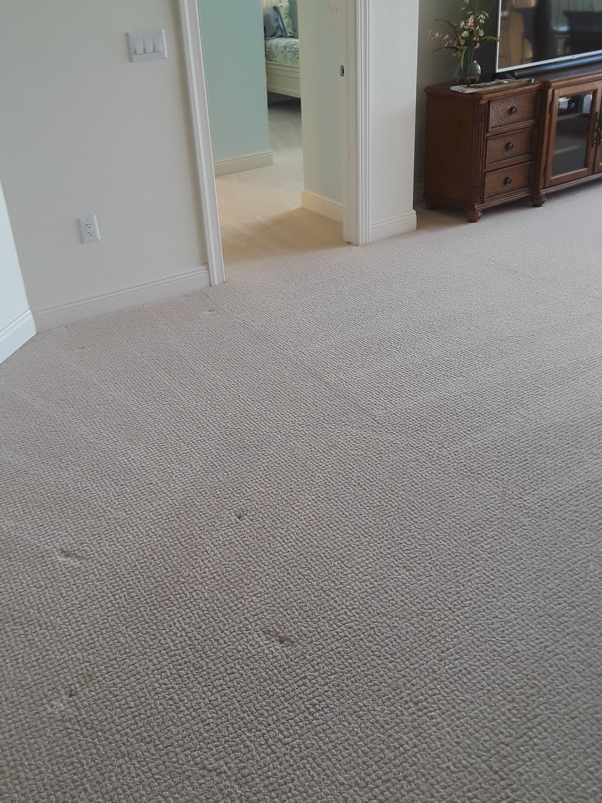 Carpeted living room with doorway to hall and a wooden sideboard on the right.