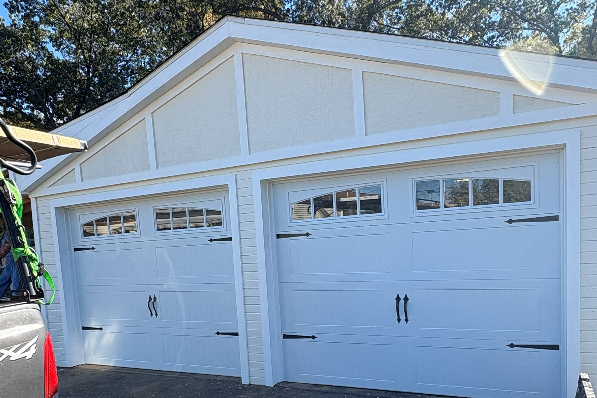 White garage with two doors and windows, under a white gabled roof.