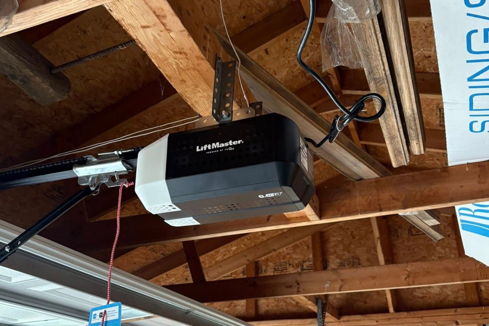 Garage door opener mounted on wooden rafters.