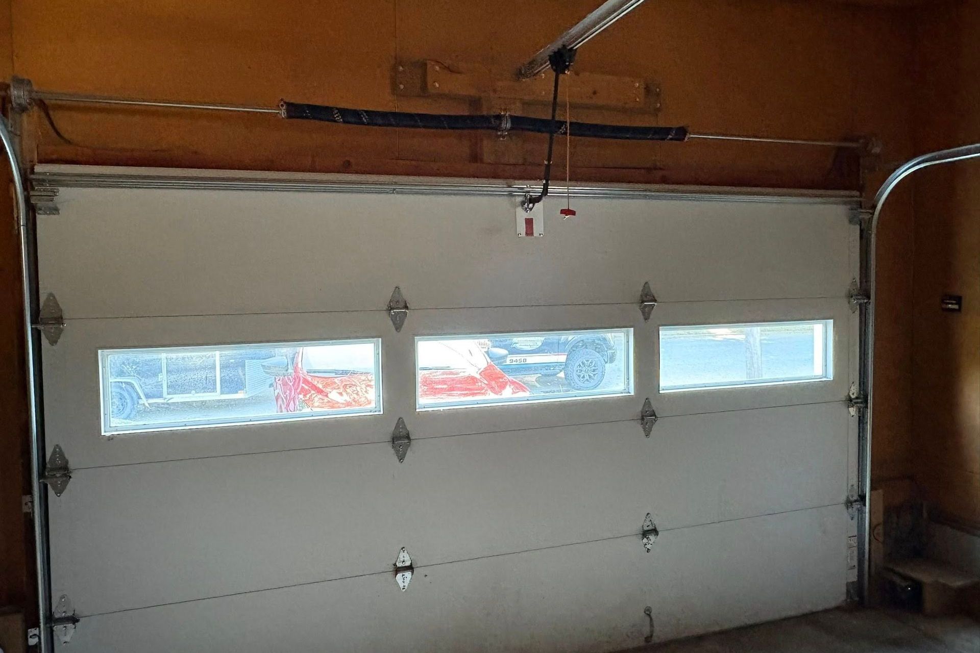 White garage door with three frosted windows, hardware, and ceiling track.