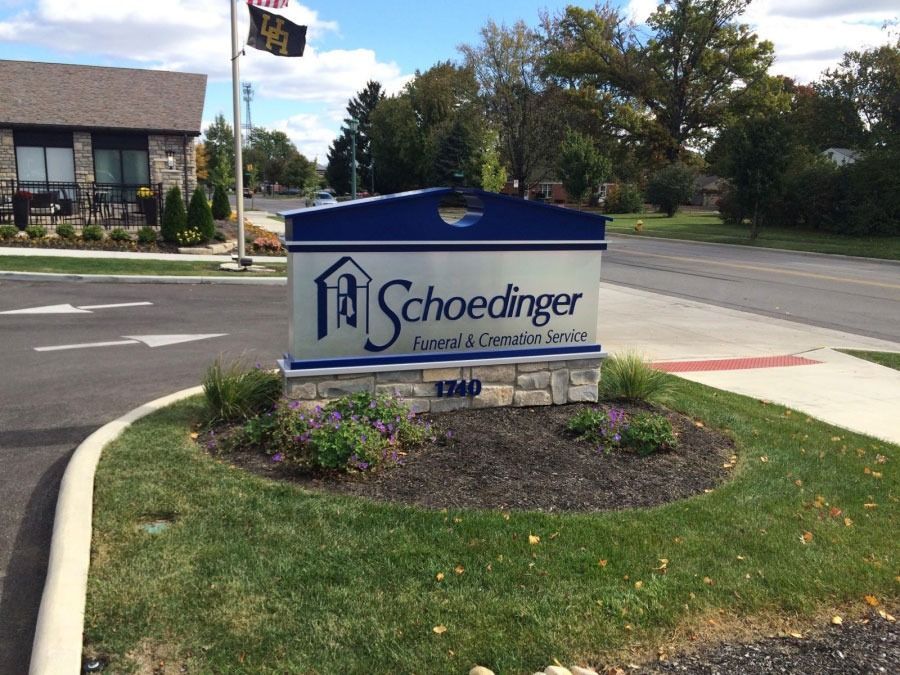 Sign for Schoedinger Funeral & Cremation Service, a blue and silver sign with the address, in front of the building.