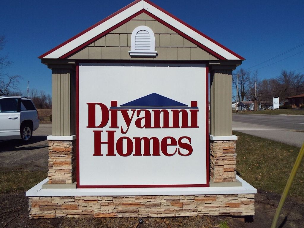 Sign for Divanni Homes, displaying company name in burgundy with a blue roof graphic.