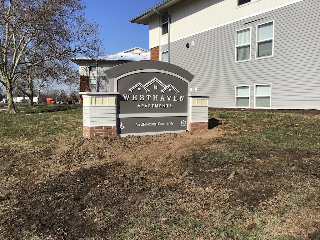 Sign for West Haven Apartments on a grassy lawn, with building in the background.