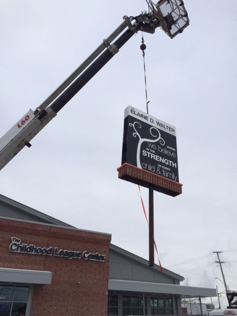 A crane lowering a sign that reads 