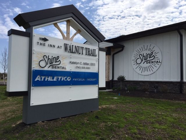 Sign for The Inn at Walnut Trail and Shine Dental, with a building featuring a Shine Dental logo.