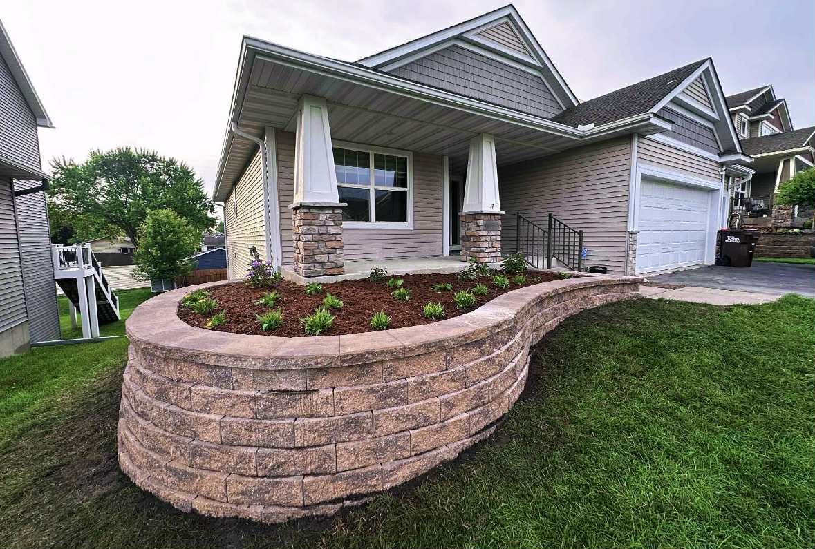 House exterior with a retaining wall flower bed and green lawn.
