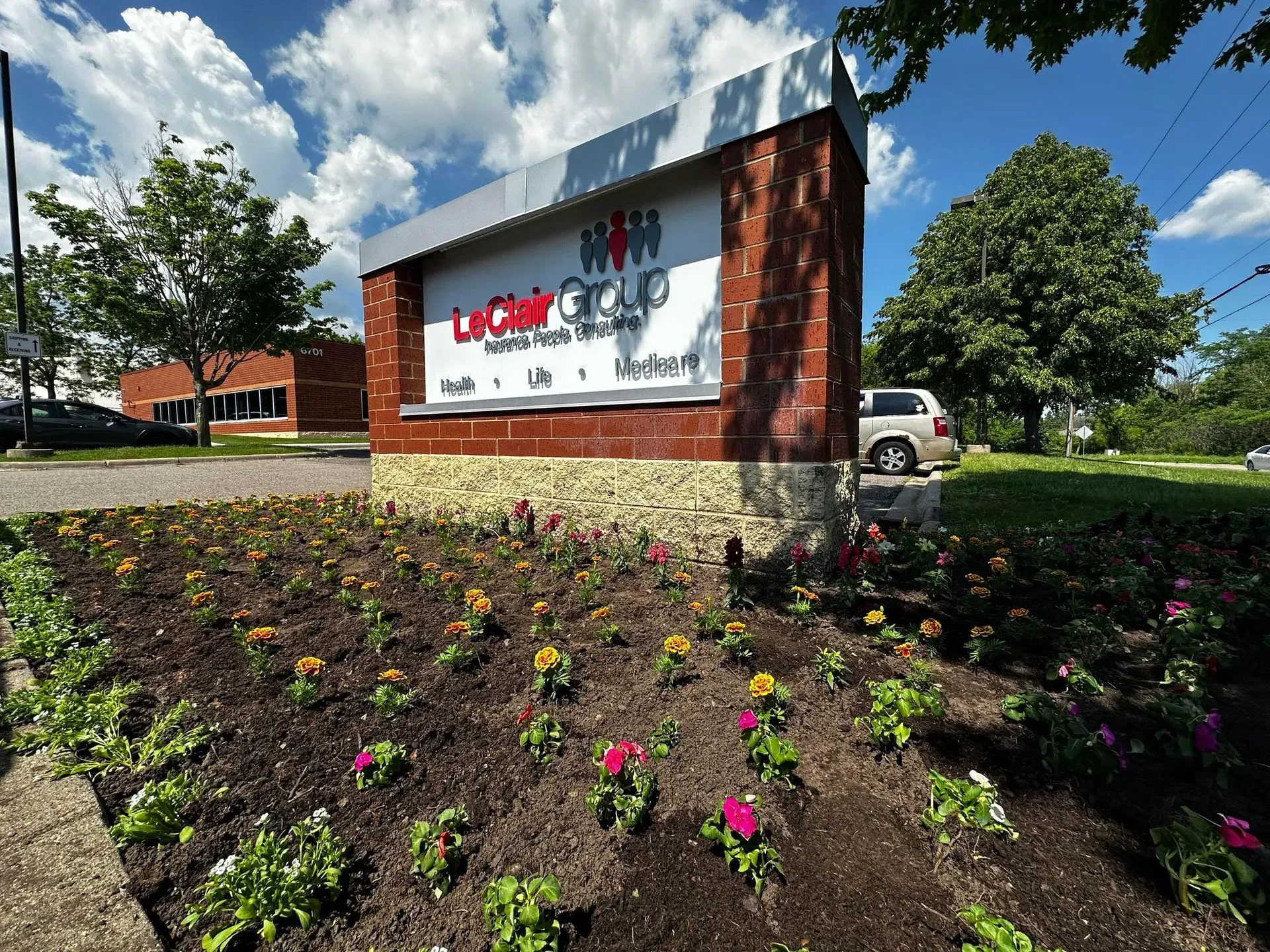 Sign for Latham Group, brick and stone base with a flower bed in front.