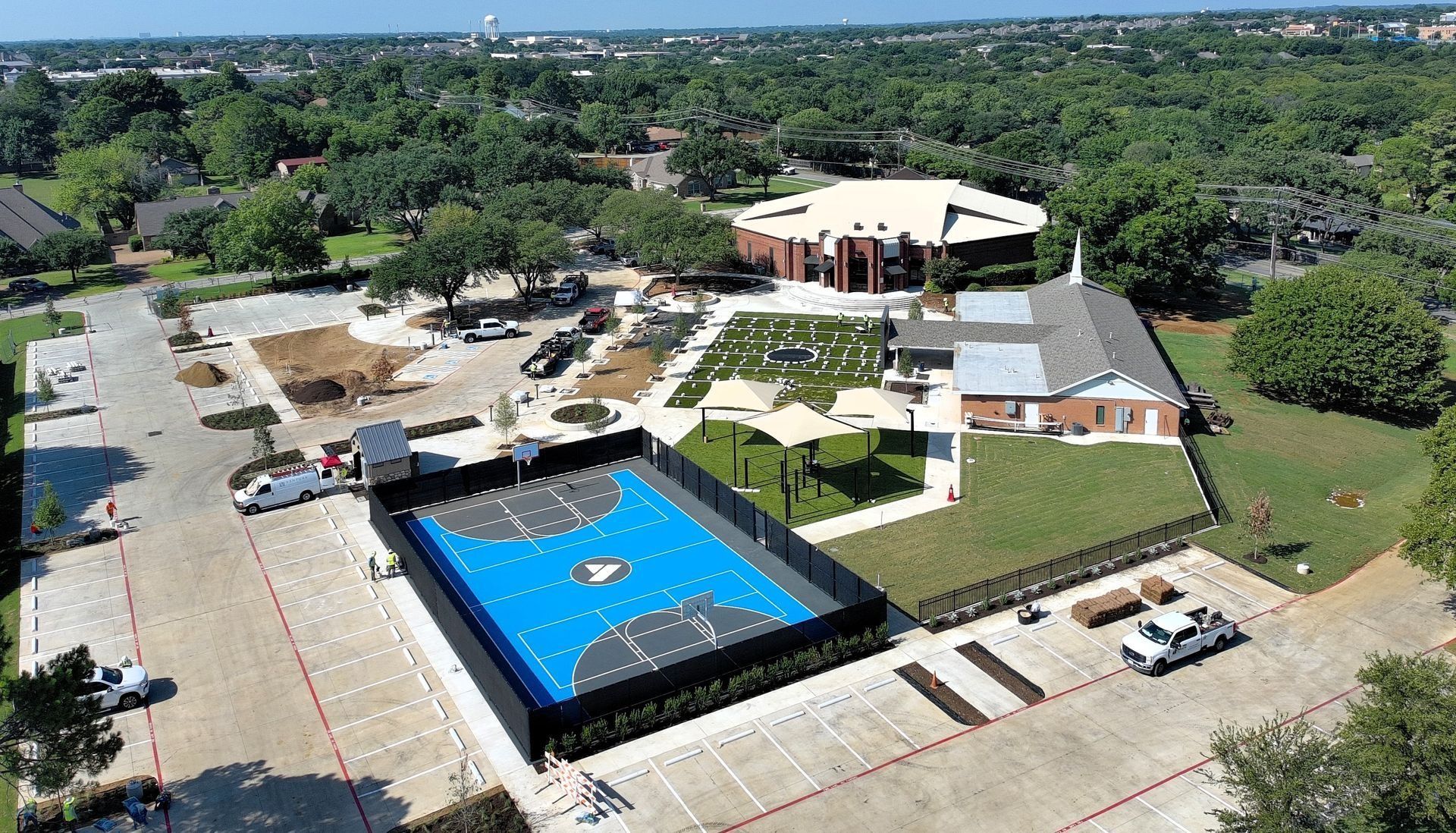 Aerial view of a large property with a blue outdoor pool, buildings, and surrounding trees and lawns