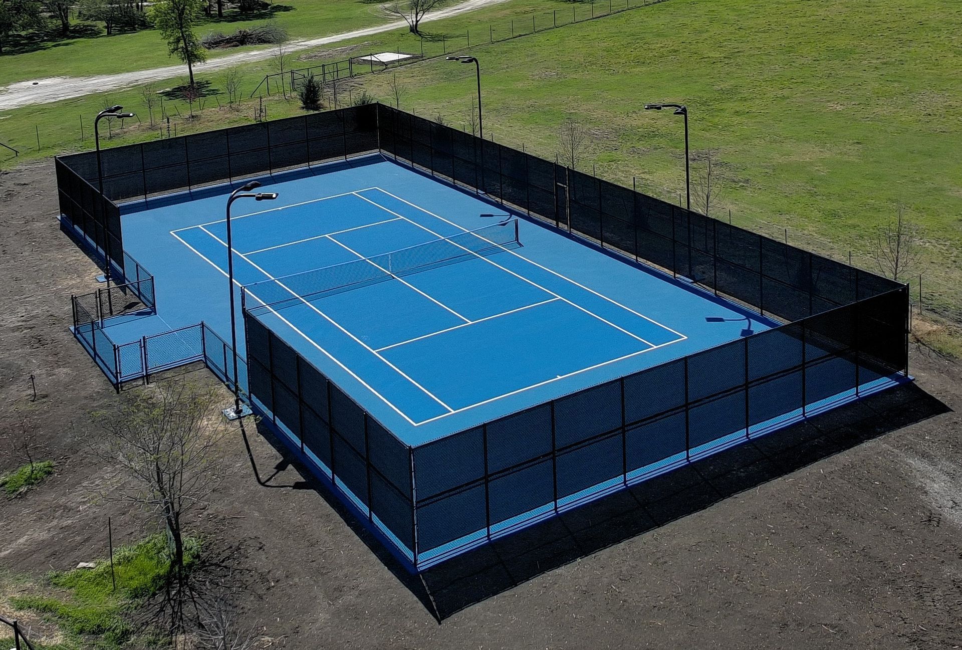 Large indoor space with beige ground and black fenced areas, lit by overhead lights.