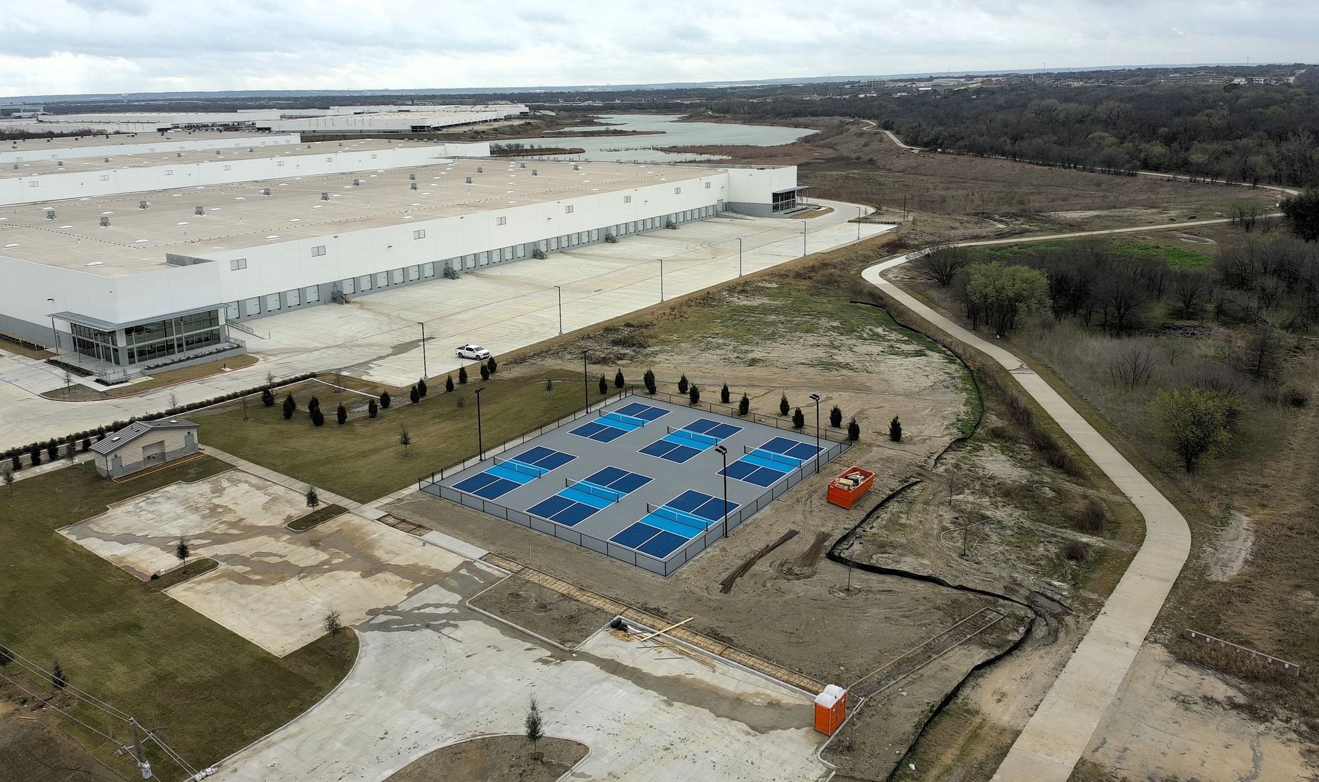 Aerial view of a large warehouse complex with a solar panel array and walking path.