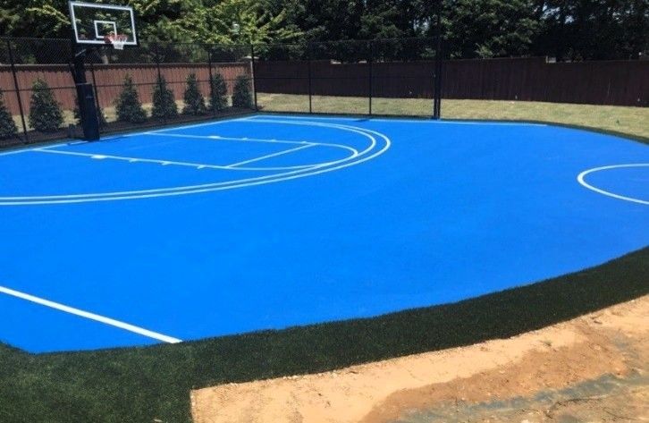 Blue outdoor basketball court with white lines and a basketball hoop.