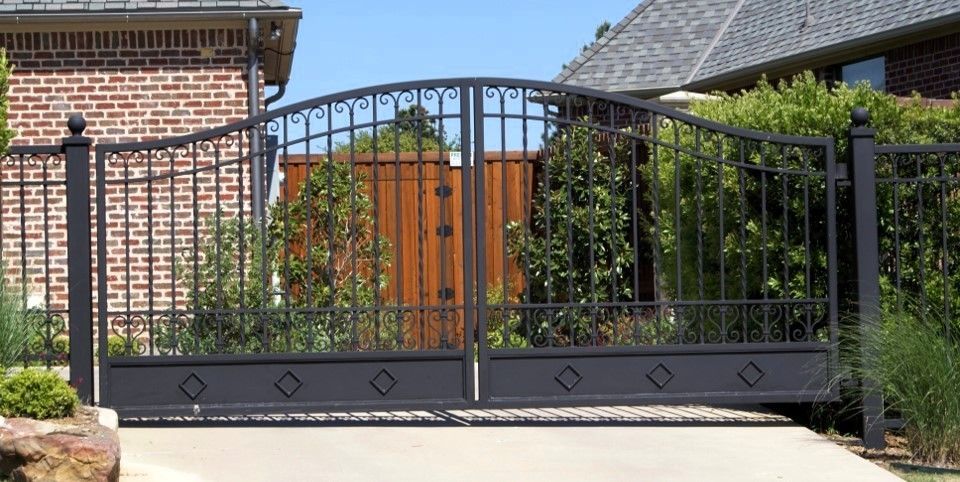 Black wrought iron gate in front of a house.