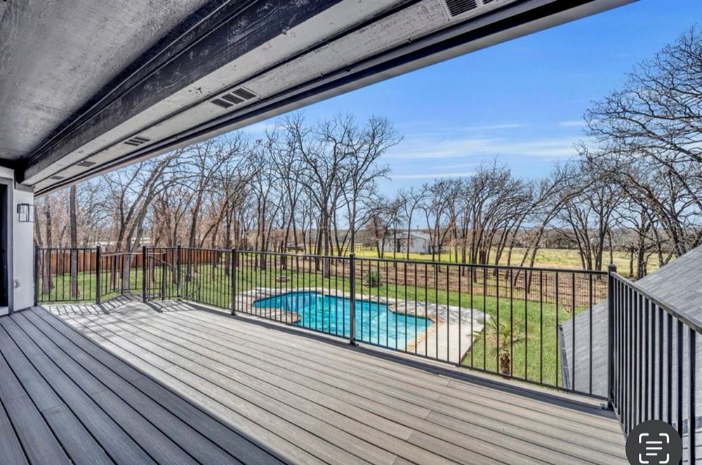 Deck overlooking a pool, fenced yard, and bare trees under a blue sky.