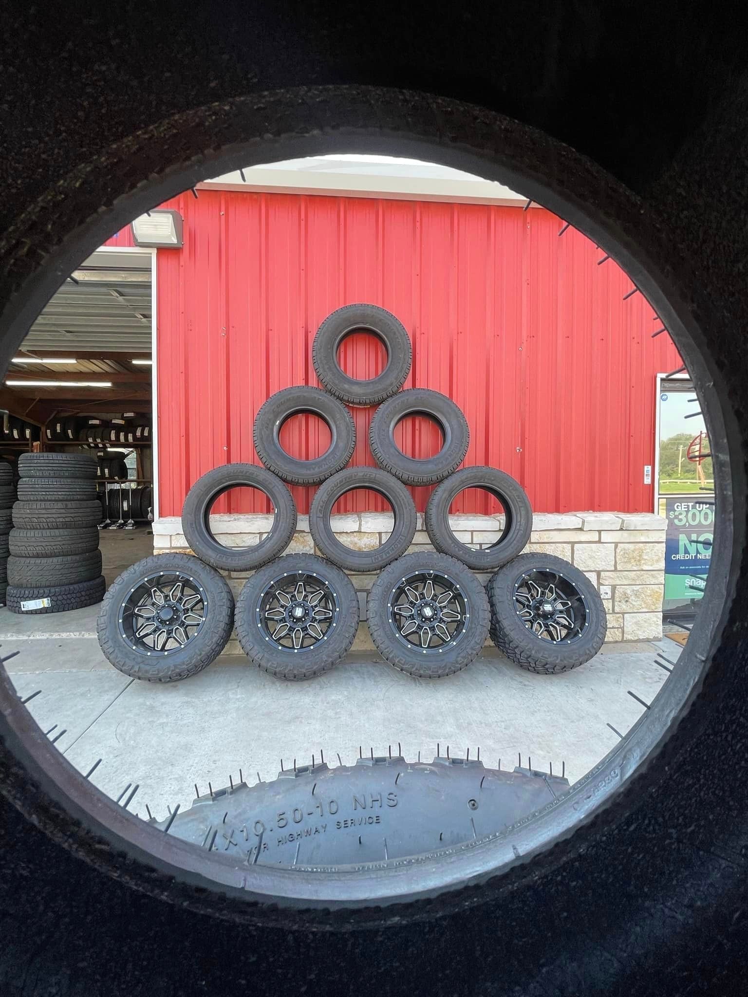 A pile of tires are stacked on top of each other in front of a red building