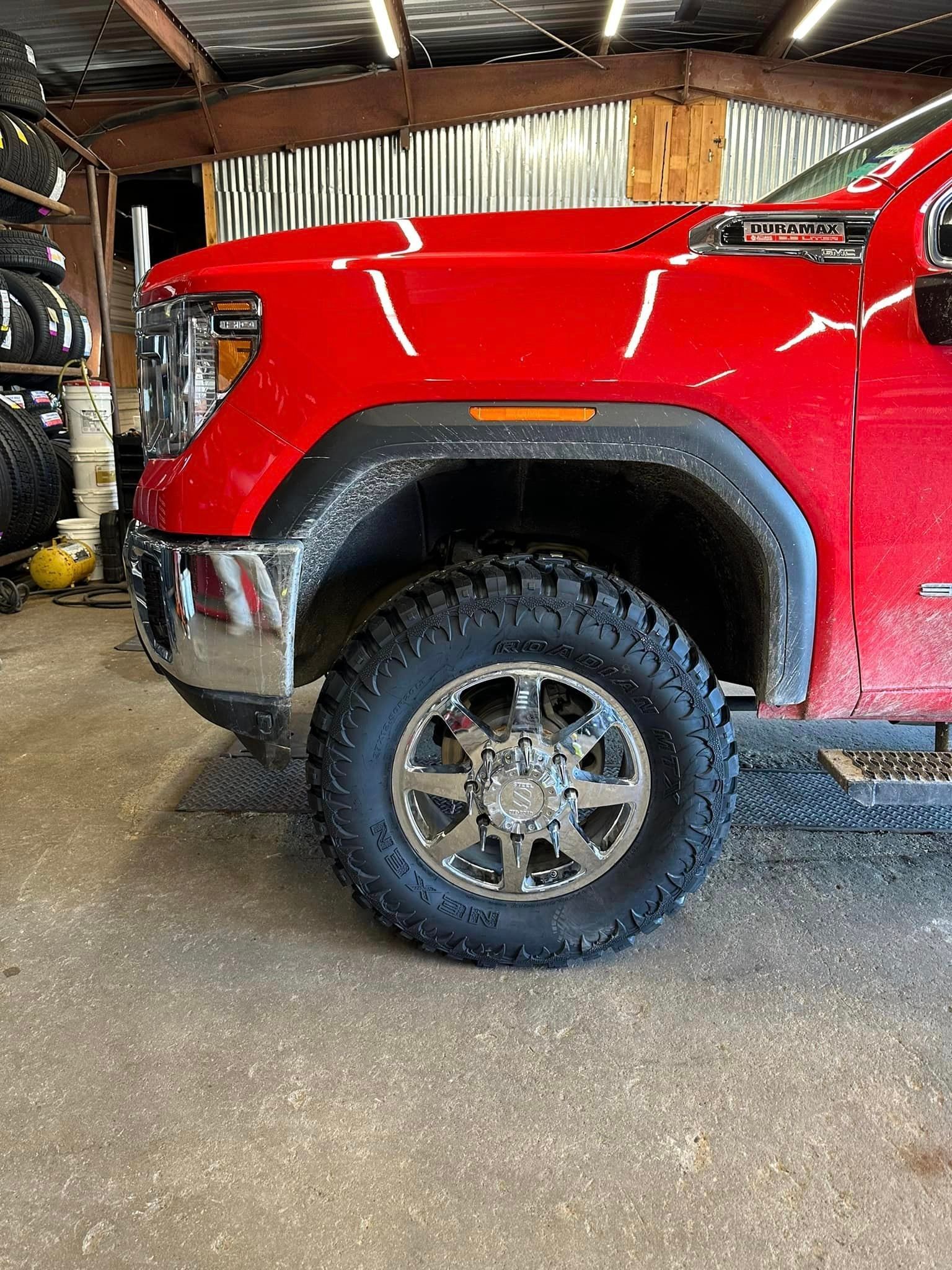 A red truck is parked in a garage with a tire on it