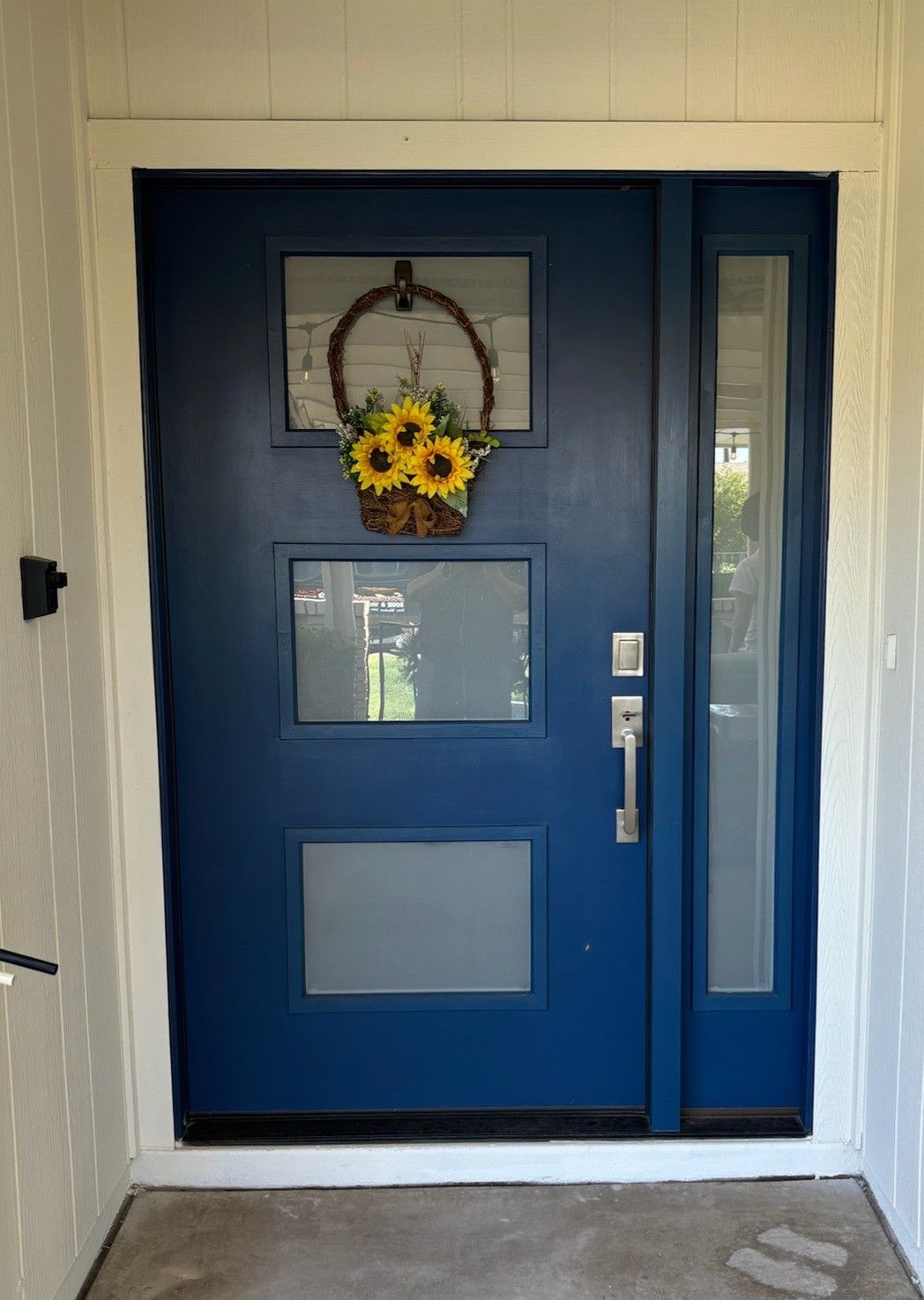 A blue door with a basket of sunflowers hanging on it.