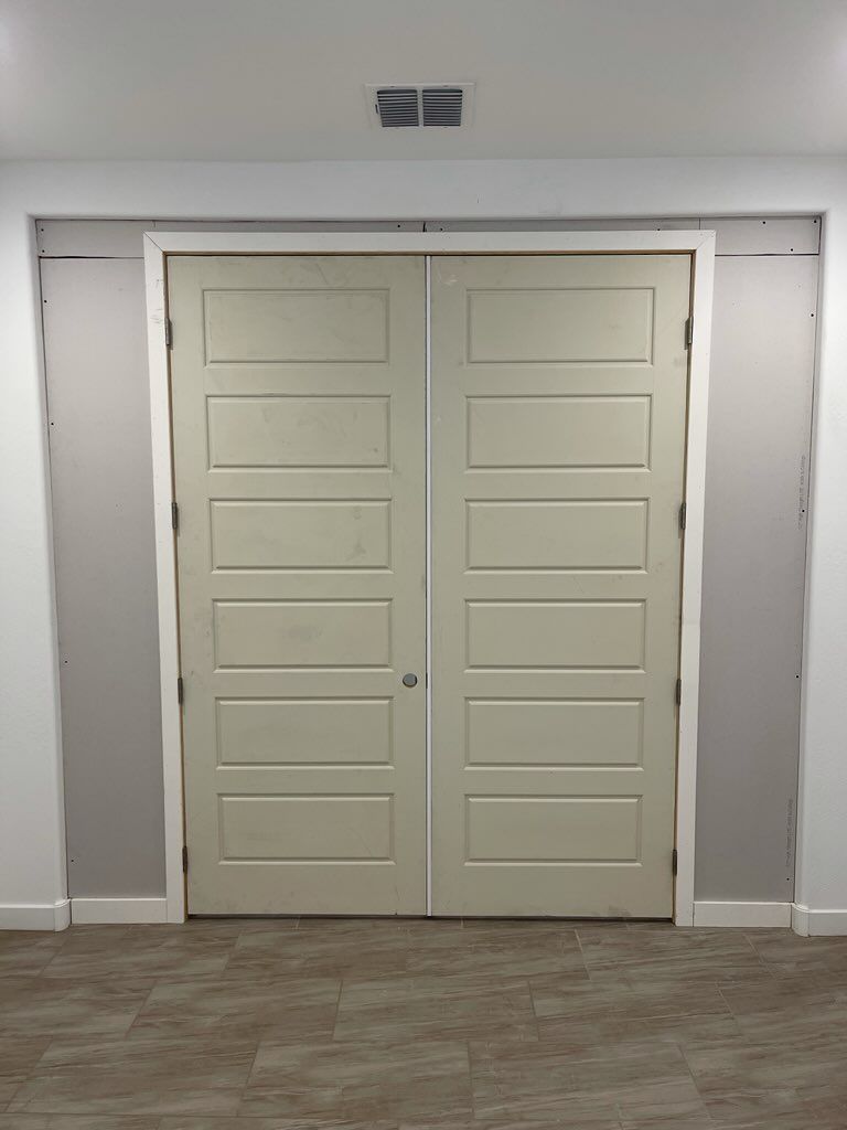 A pair of white doors in a room with a wooden floor.