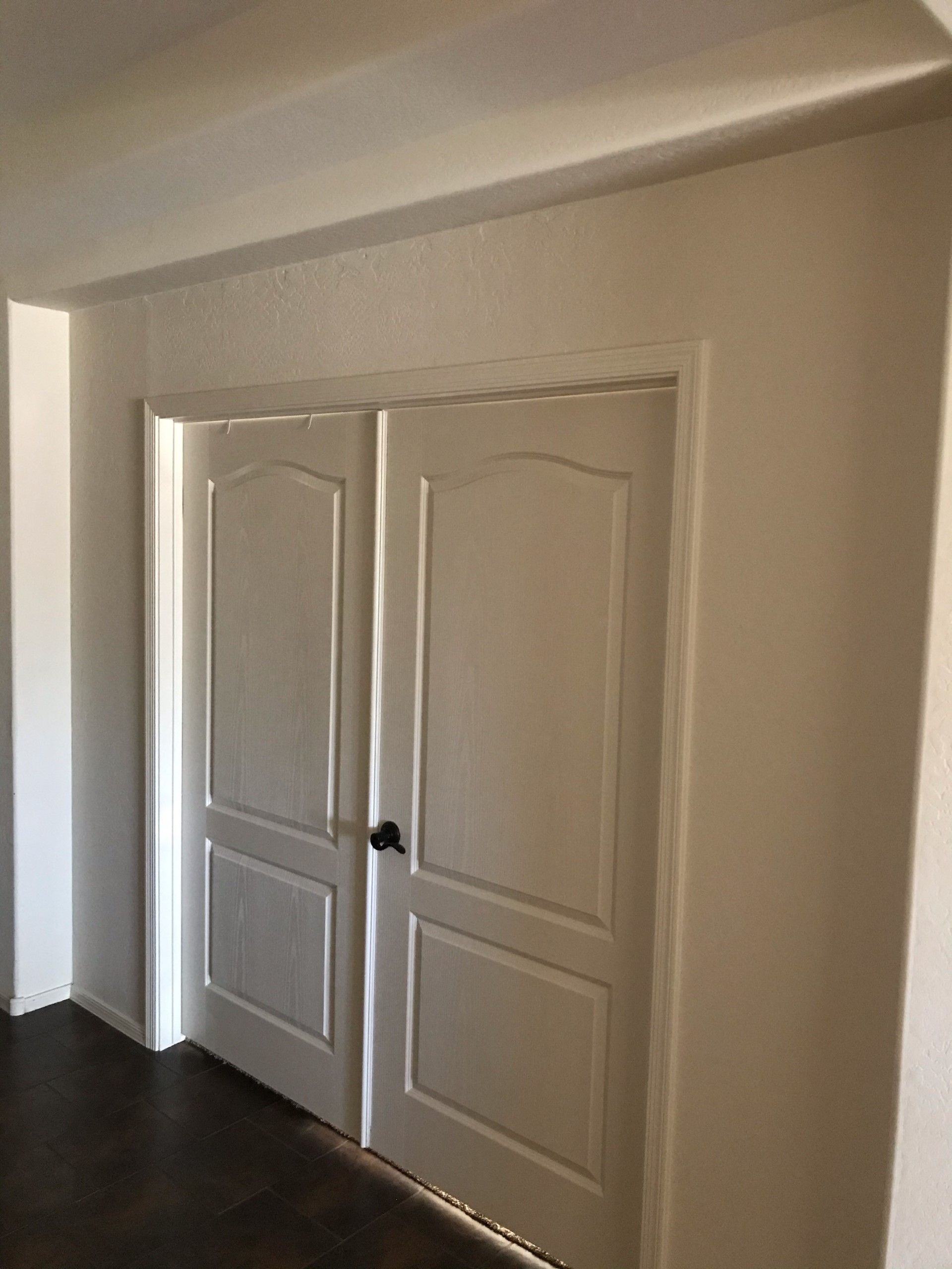 A pair of white doors are open in a hallway.