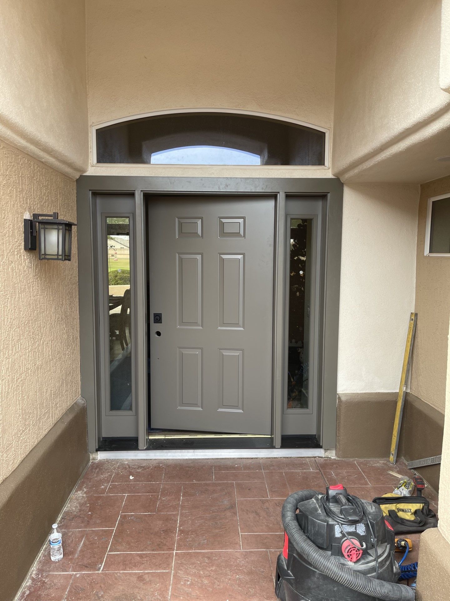 The front door of a house is being painted and a vacuum cleaner is sitting in front of it.
