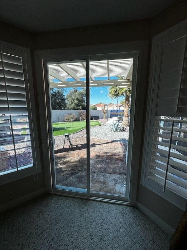 A room with a sliding glass door and shutters