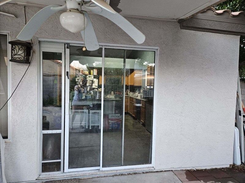 A sliding glass door with a ceiling fan above it before