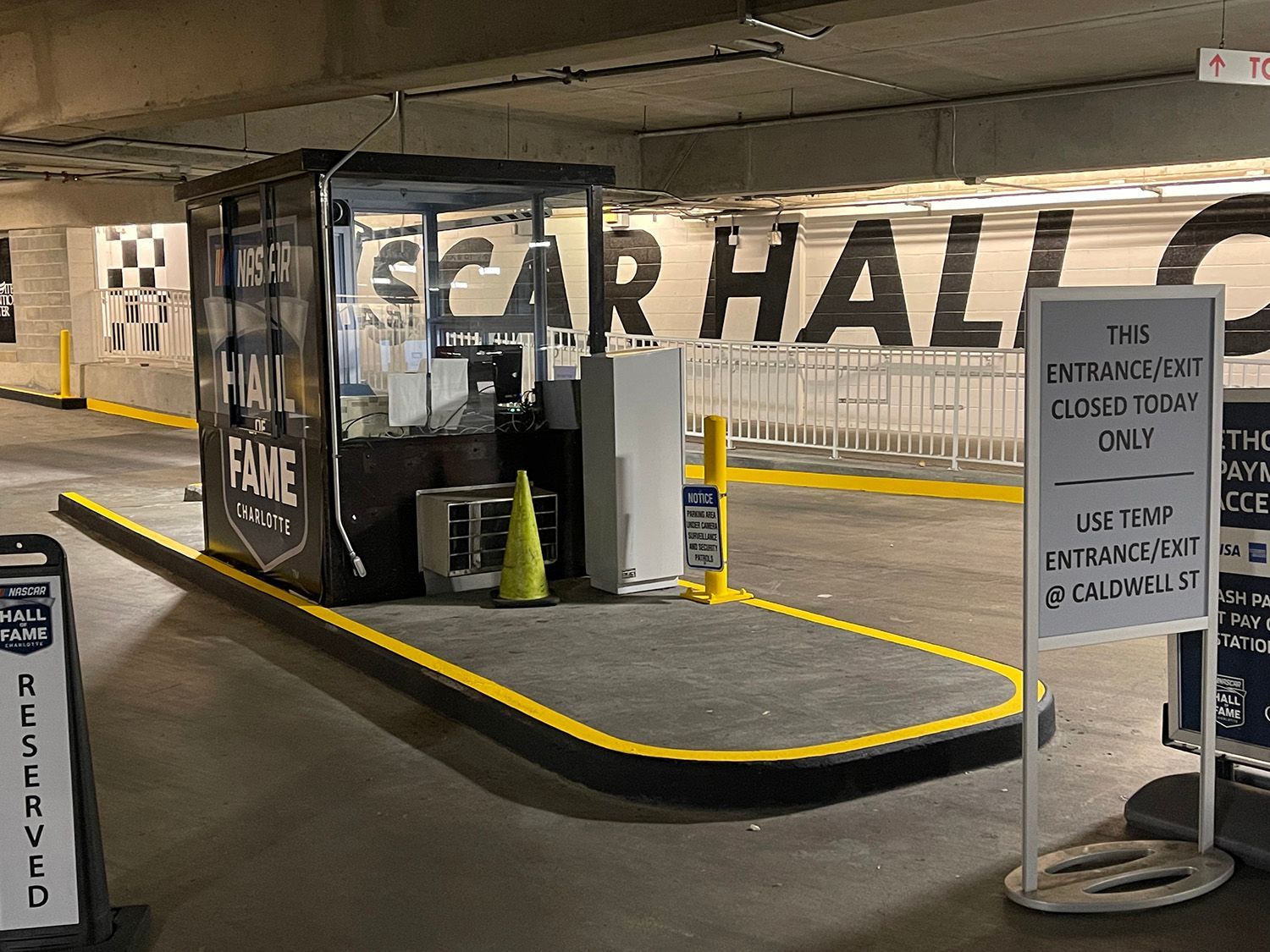 A parking garage entrance with a booth, a sign stating 