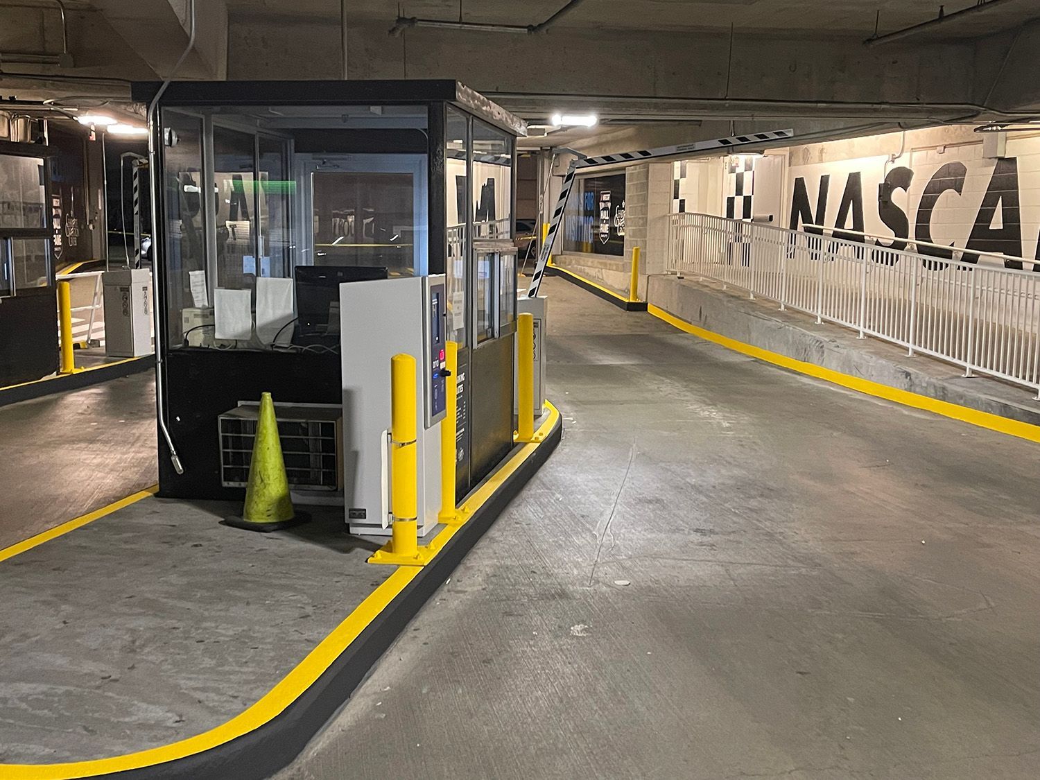 A parking garage entry with a booth, barriers, and signage reading 