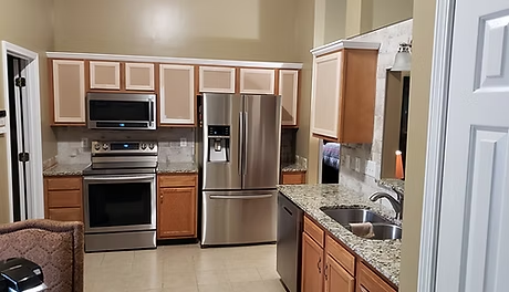 Kitchen with stainless steel appliances, light wood cabinets, and granite countertops. A double door refrigerator and stove are centered.