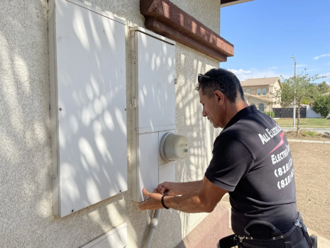 Person adjusting a wall-mounted utility box beside a house in daylight