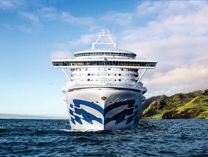 Cruise ship on the ocean with a blue and white design, headed towards the viewer.