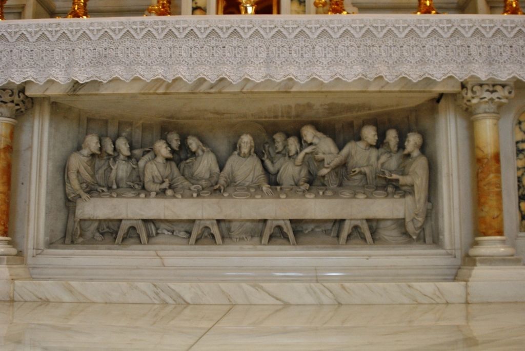 There is a statue of the last supper on the altar of a church.