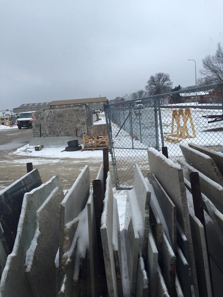 A stack of concrete blocks covered in snow in front of a chain link fence