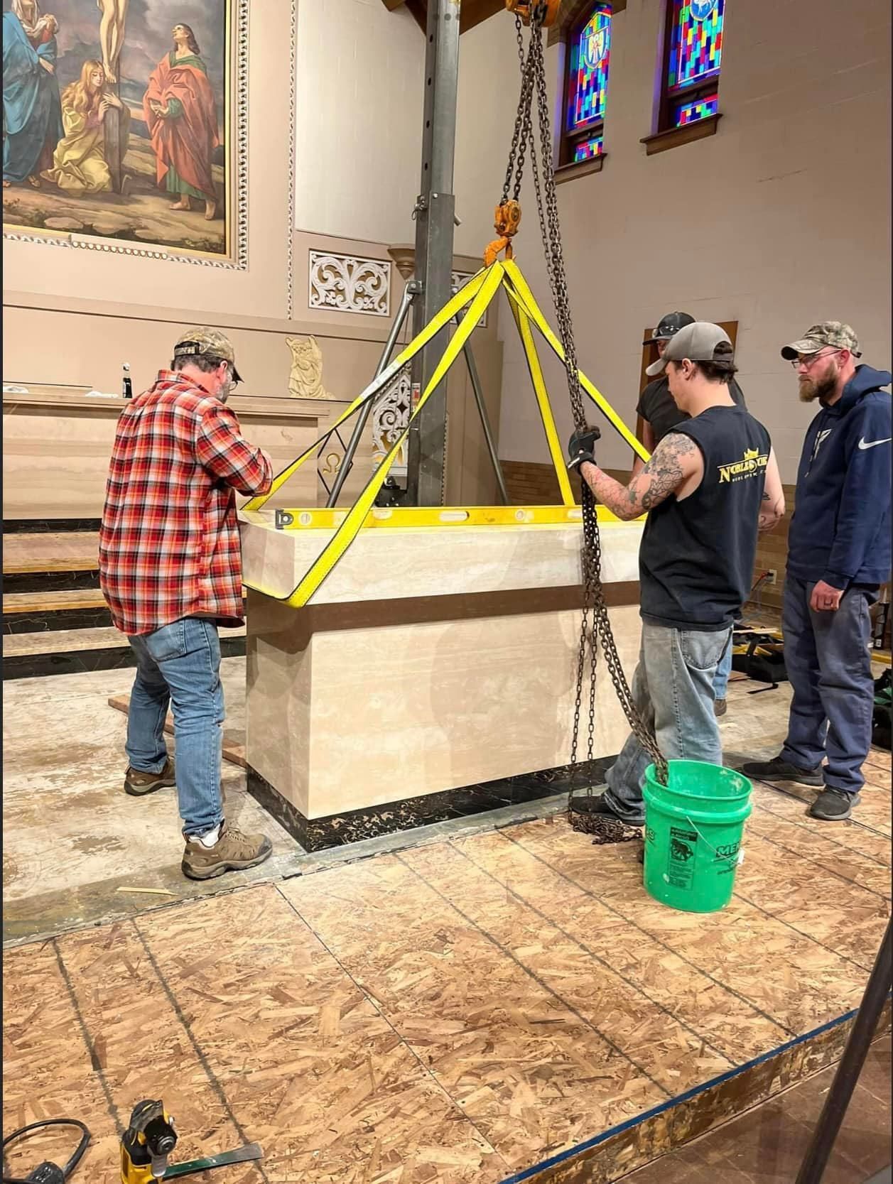 A group of men are working on a statue in a church.