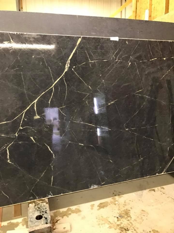 A large black marble slab is sitting on top of a wooden table.