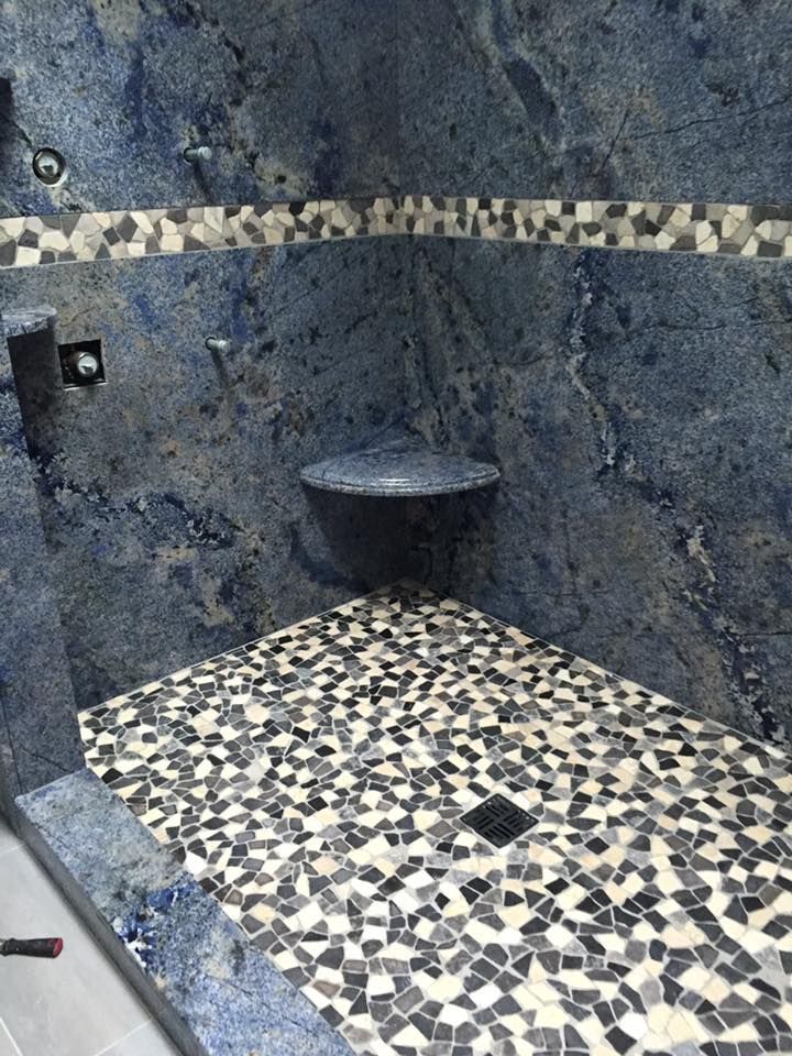 A shower with a blue wall and a mosaic floor