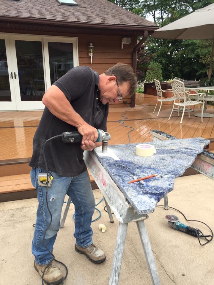 A man is using a drill to cut a piece of wood.