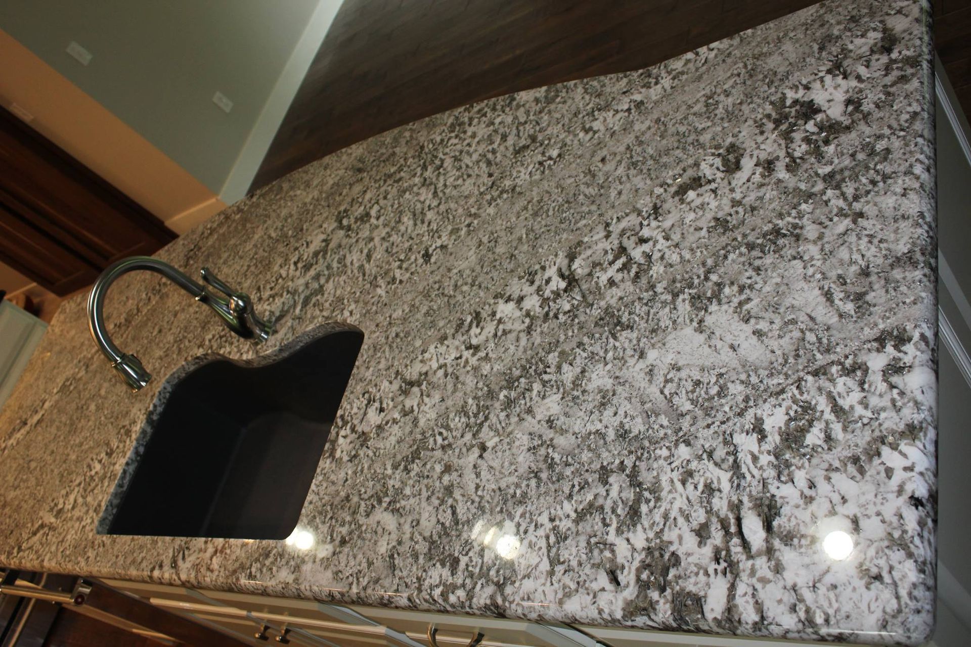 A kitchen with a granite counter top and a black sink.