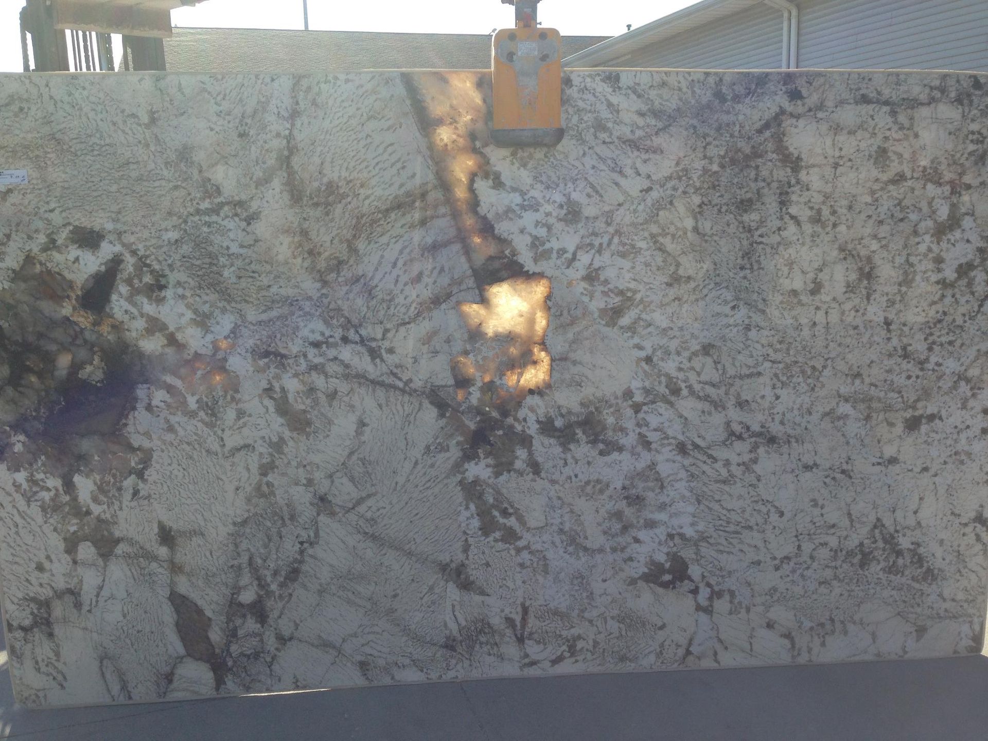 A large slab of granite is being lifted by a crane.