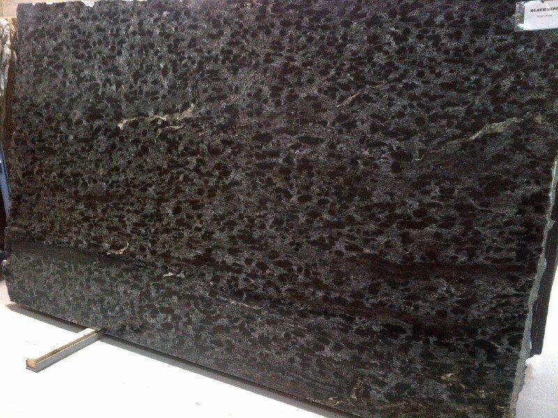 A large black granite slab is sitting on top of a white table.