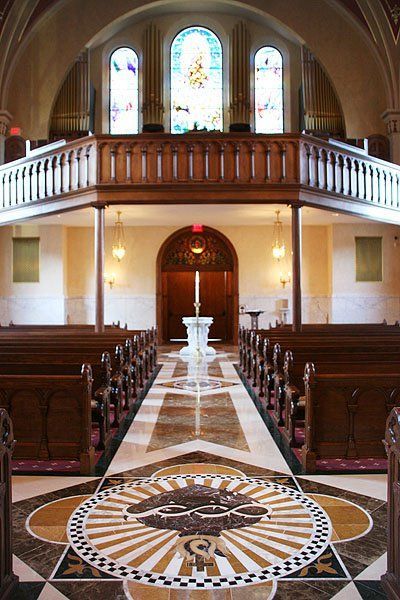 The inside of a church with a marble floor and stained glass windows.