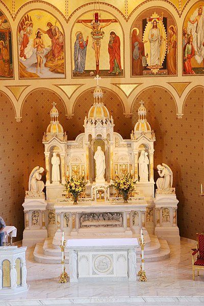 A church with a large altar and paintings on the wall.