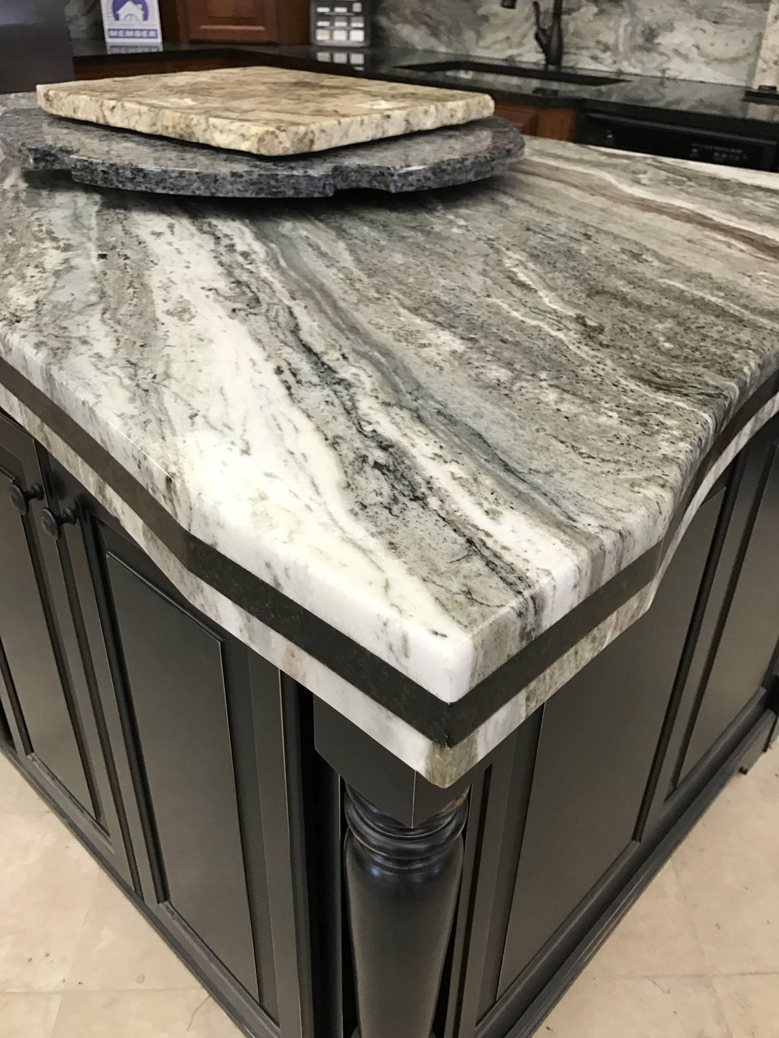 A kitchen island with a granite counter top and black cabinets.