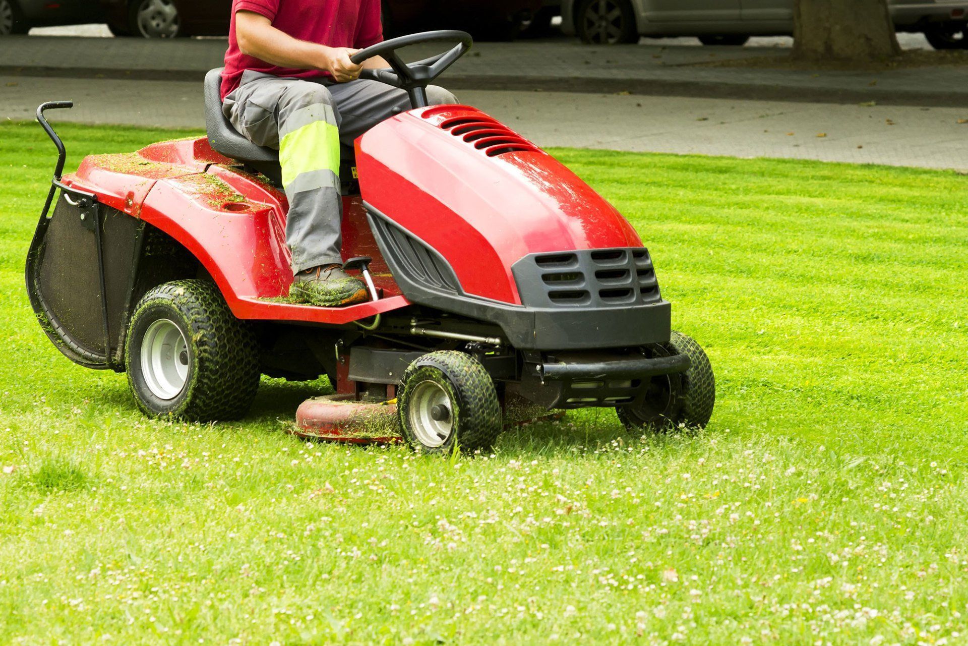 A man is riding a lawn mower on a lush green lawn.