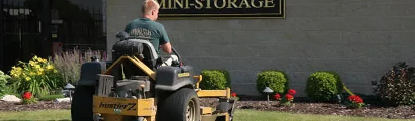 A man is riding a lawn mower in front of a building.