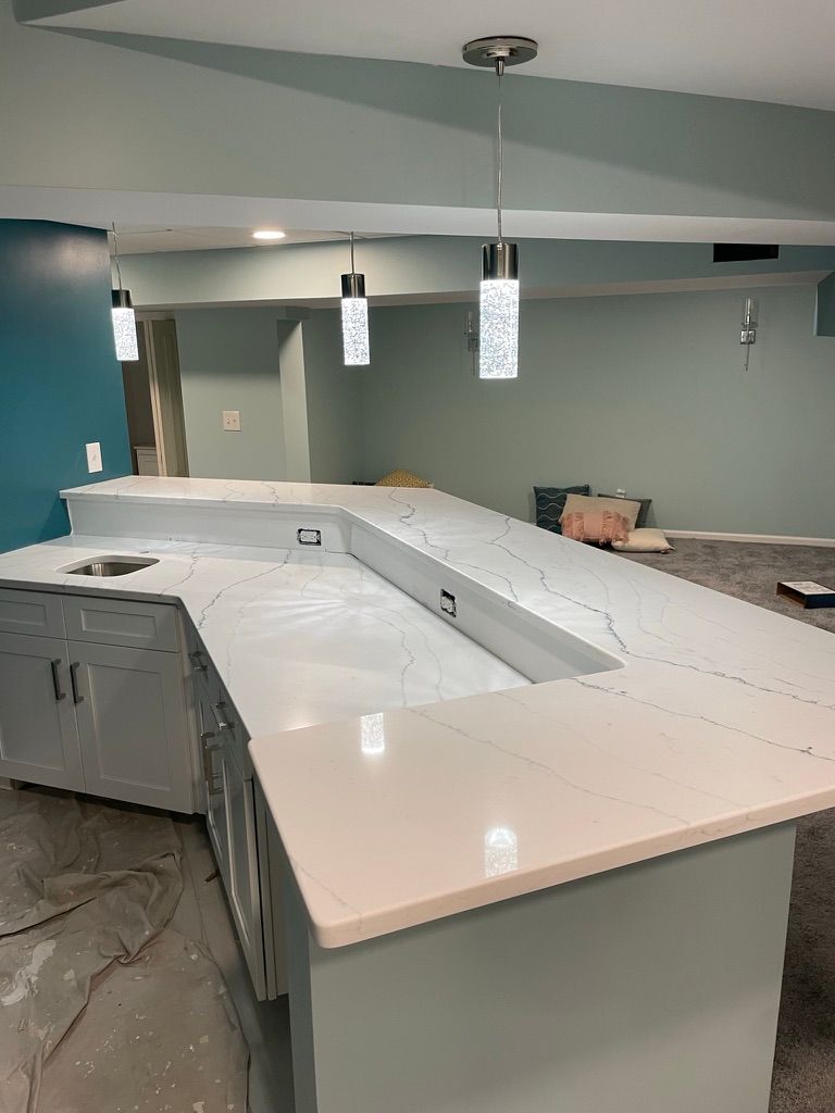 A modern bar with white countertop and pendant lights; turquoise and pale green walls.