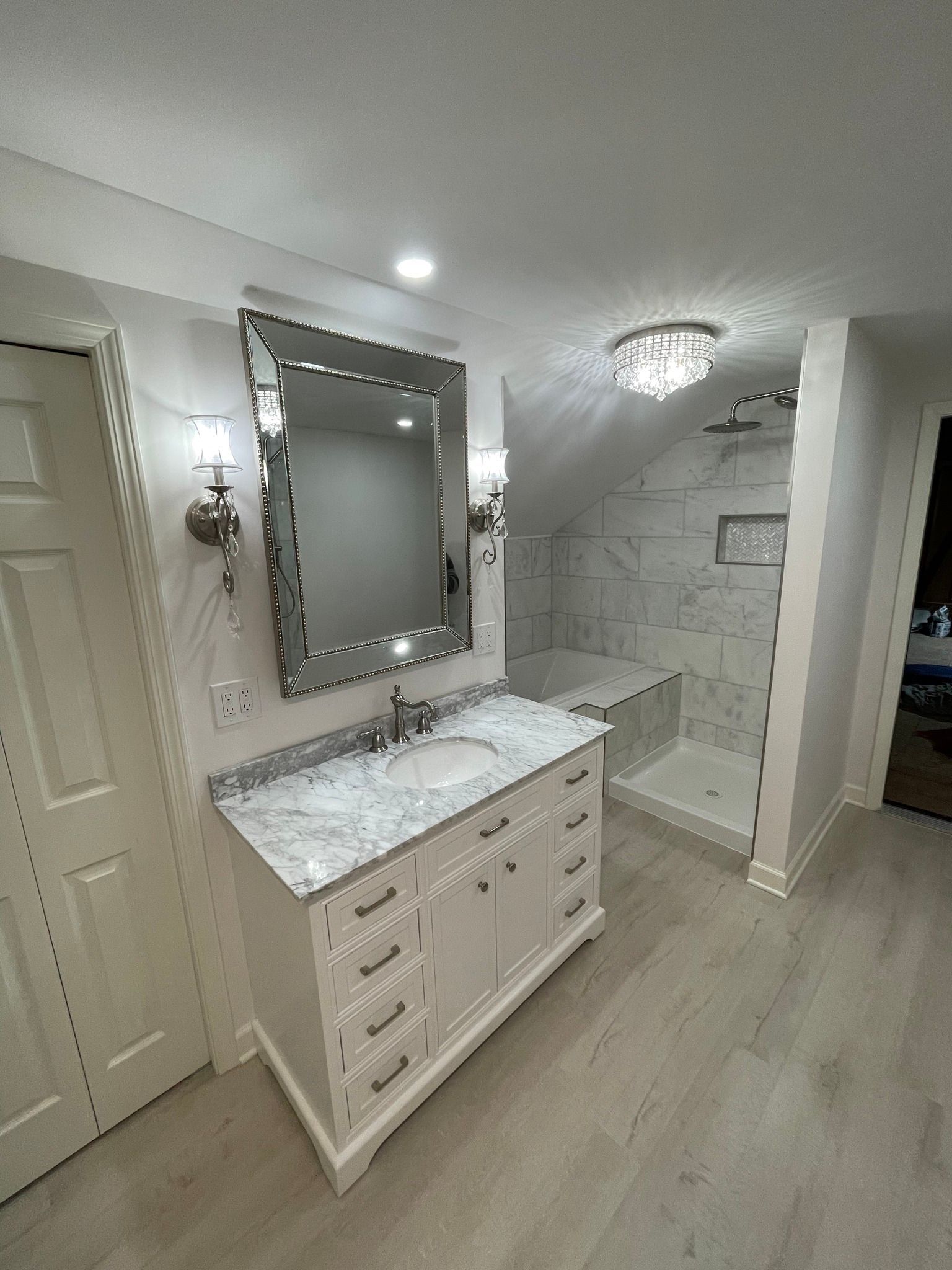 Bathroom with white vanity, marble countertop, large mirror, and tiled shower.